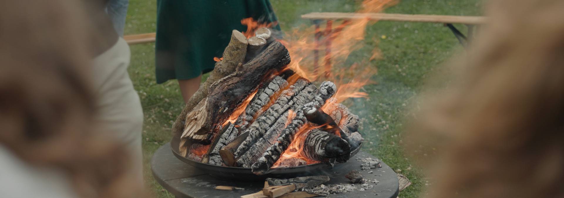 Brandende vuurschaal omringd door aanwezigen tijdens een afscheidsceremonie in de buitenlucht.